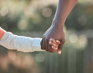 Shot of a young boy holding on to his father's hand while walking outside
