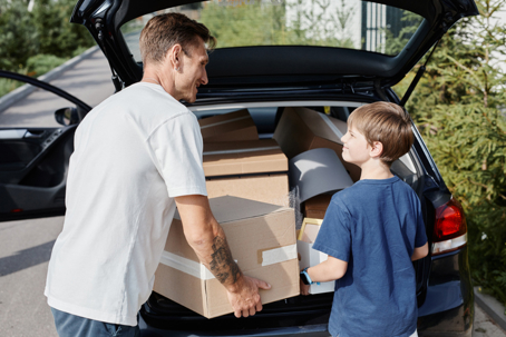 father and son packing car with moving boxes