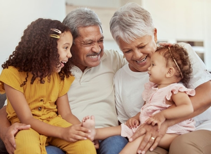 Mixed race grandparents enjoying weekend with granddaughters in home living room