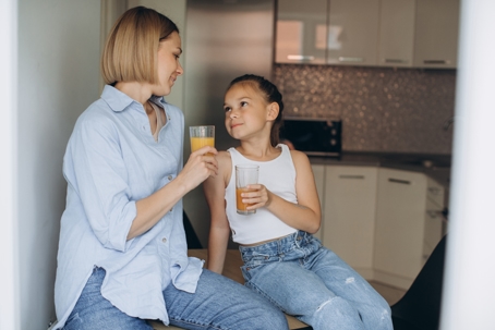 mother and daughter drinking juice in their kitchen