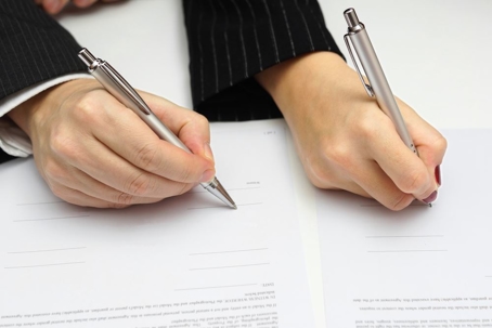man and woman signing document or prenuptial agreement