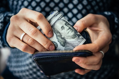Hands holding us dollar bills and small money pouch