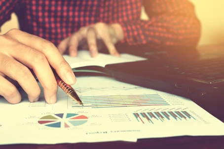 Close up businessman hand writing with calculating at home office.